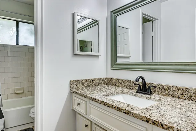 a bathroom with a granite countertop sink and a mirror