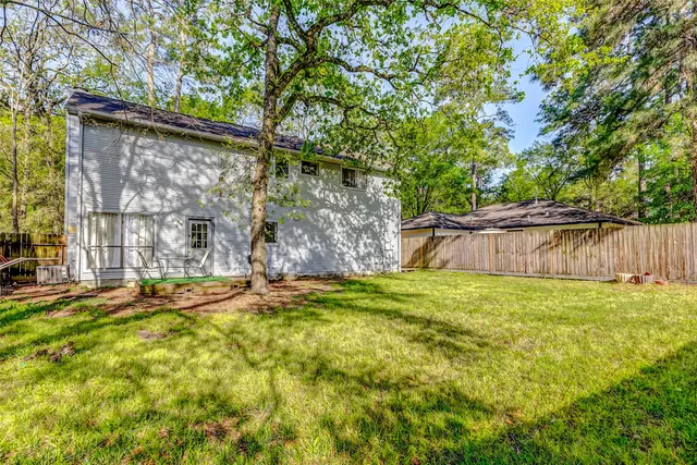 a backyard of a house with table and chairs wooden floor and fence