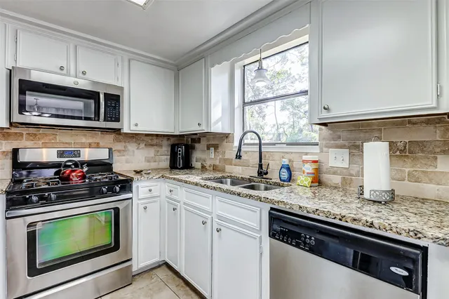 a kitchen with granite countertop a sink a stove and microwave