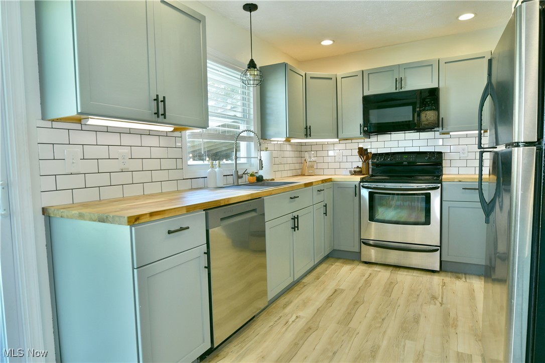 4400 Ridge Road Cortland, OH 44410 - Photo 27 of 50 Kitchen featuring pendant lighting, stainless steel appliances, wooden counters, light wood-style flooring, and backsplash