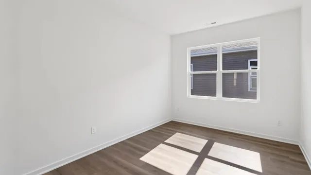 a view of an empty room with wooden floor and windows