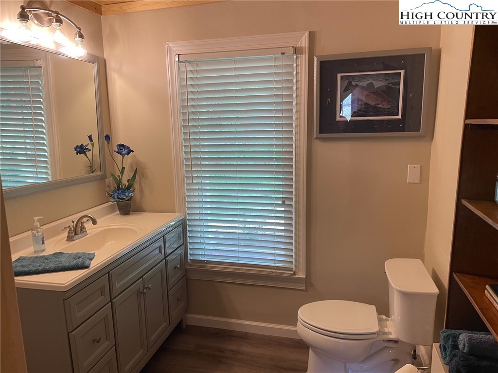 3350 Teaberry Road Lansing, NC 28643 - Photo 14 of 30 a bathroom with a granite countertop toilet a sink a mirror and a window