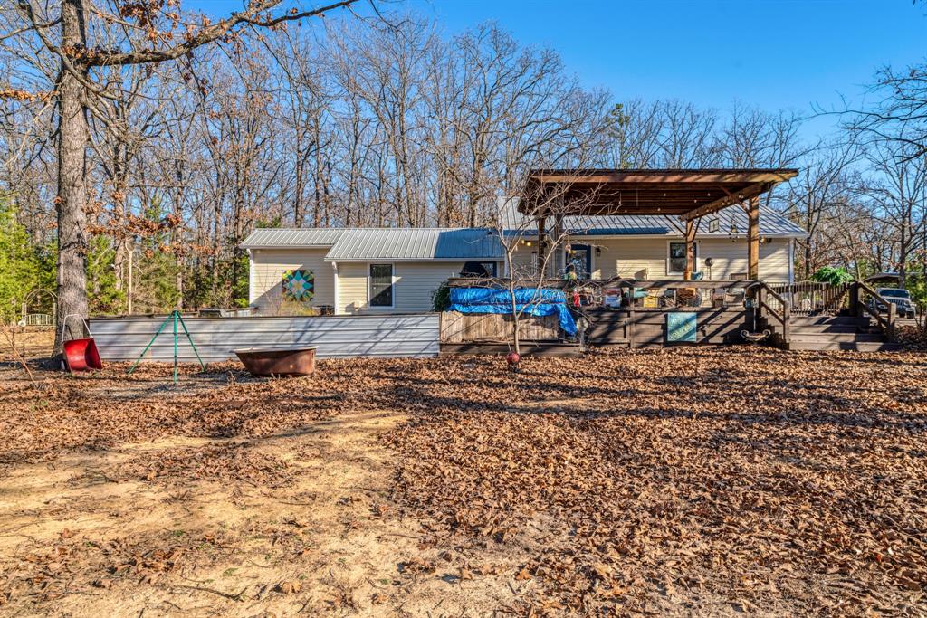 1431 County Road Paris, TX 75462 - Photo 20 of 27 a view of a wooden house with a yard and furniture