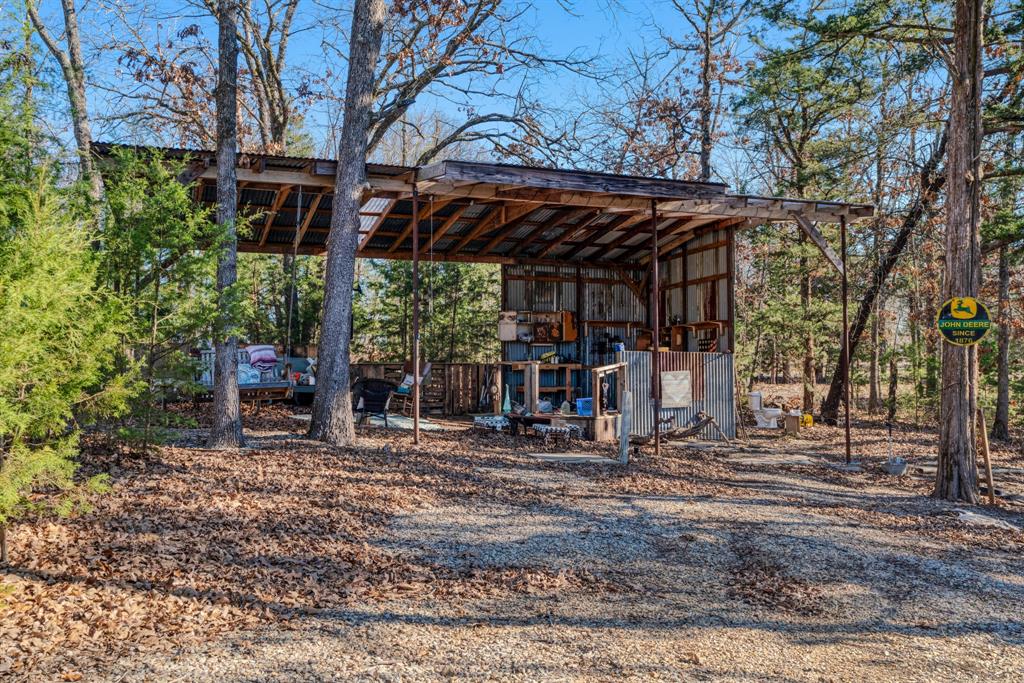 1431 County Road Paris, TX 75462 - Photo 25 of 27 a view of a patio with table and chairs under an umbrella with a large tree