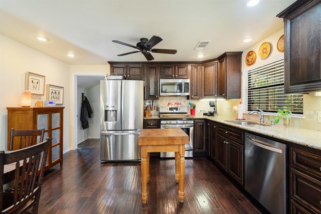 1431 County Road Paris, TX 75462 - Photo 7 of 27 a kitchen with stainless steel appliances granite countertop a refrigerator a stove top oven a sink dishwasher and white cabinets with wooden floor