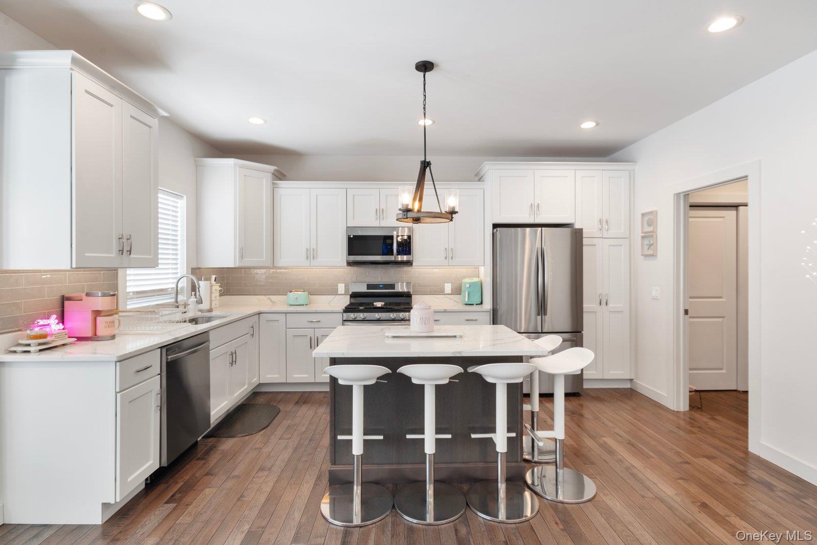 65 Doane Avenue Bellport, NY 11713 - Photo 8 of 37 a kitchen with a dining table chairs refrigerator and cabinets