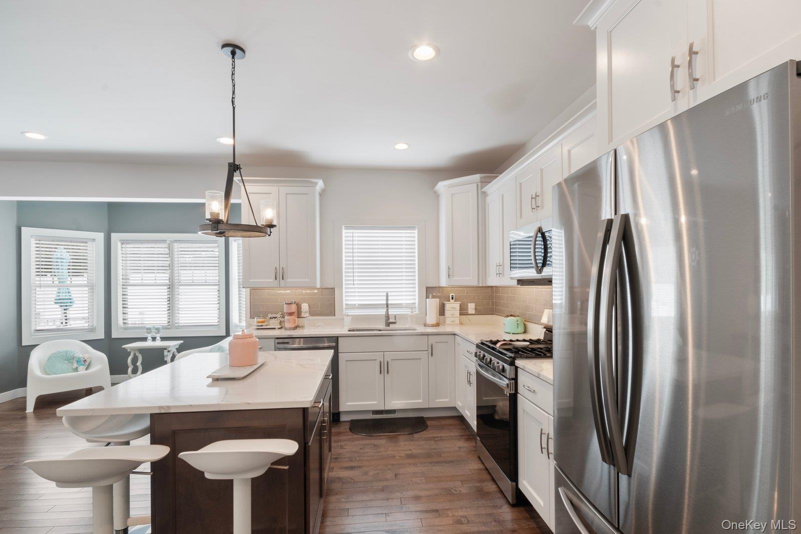 65 Doane Avenue Bellport, NY 11713 - Photo 10 of 37 a kitchen with stainless steel appliances a refrigerator a sink a stove a table and chairs