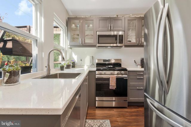 a kitchen with stainless steel appliances granite countertop a refrigerator a stove top oven and sink