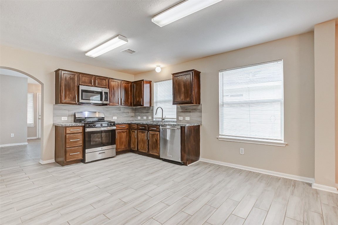 10822 Cane Grove Lane Houston, TX 77075 - Photo 20 of 44 a kitchen with stainless steel appliances granite countertop a stove a sink dishwasher a refrigerator and a microwave oven with wooden floor