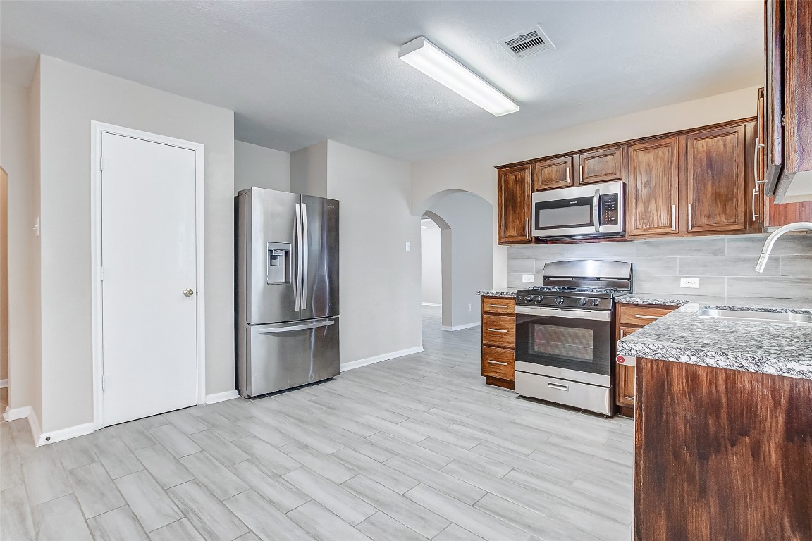 10822 Cane Grove Lane Houston, TX 77075 - Photo 21 of 44 a kitchen with granite countertop a refrigerator and a stove top oven