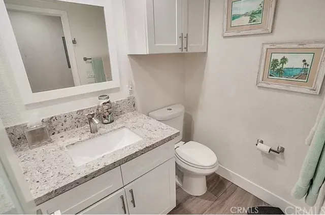 a bathroom with a granite countertop sink toilet and mirror