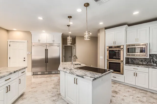 a kitchen with stainless steel appliances kitchen island granite countertop a sink a stove and a refrigerator