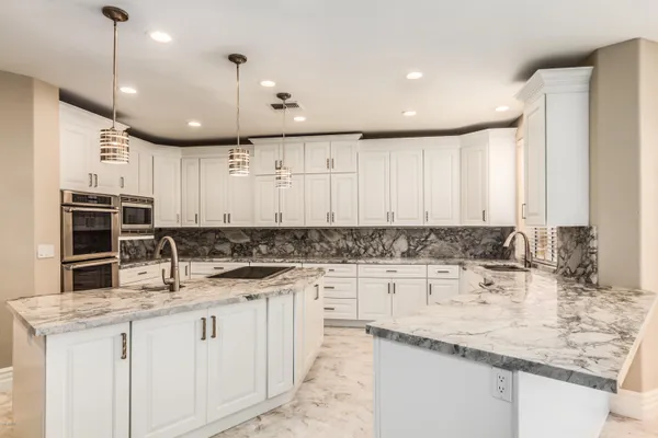 a kitchen with kitchen island granite countertop a sink a counter space appliances and cabinets