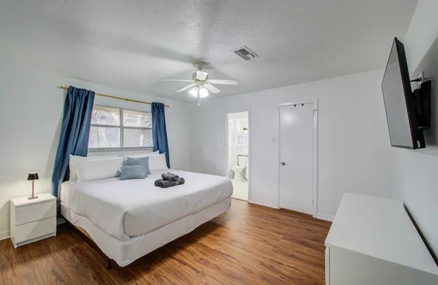 a bedroom with a bed a flat screen tv and dresser