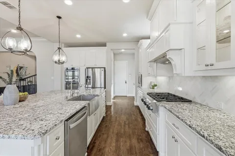 a kitchen with stainless steel appliances granite countertop a sink a stove and a wooden cabinets