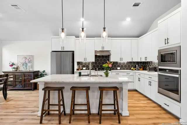 a kitchen with stainless steel appliances kitchen island granite countertop a table chairs stove and refrigerator