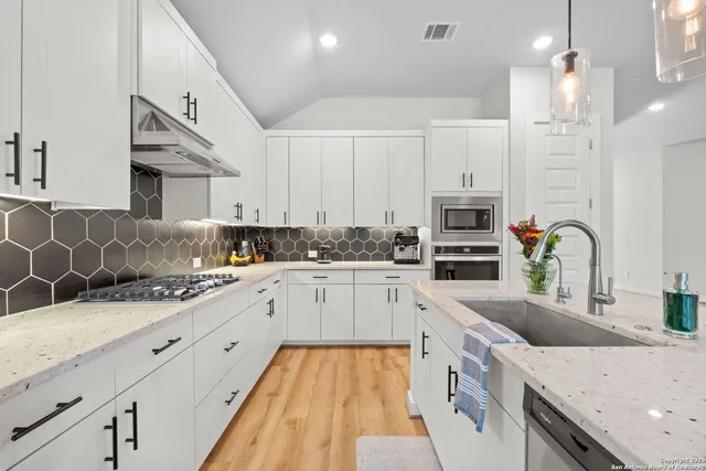 a kitchen with granite countertop a sink a counter space appliances and cabinets