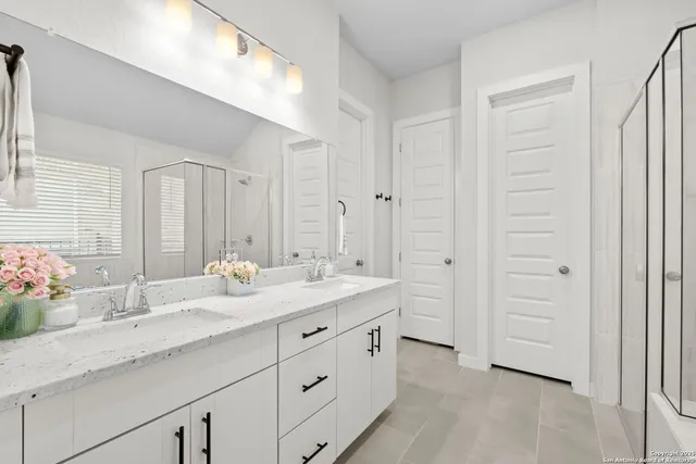 a bathroom with a double vanity sink a mirror and a shower