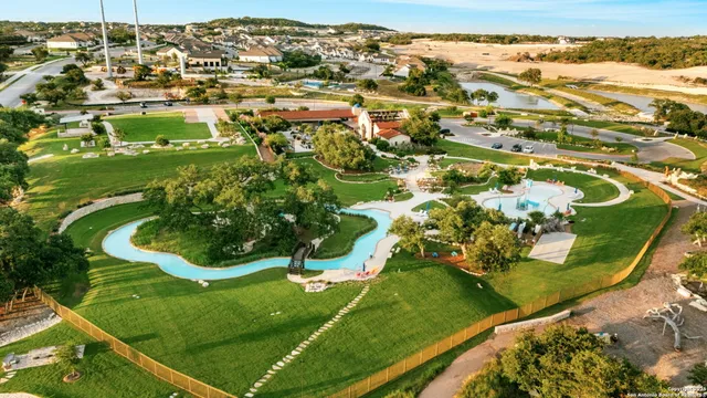 an aerial view of a residential houses with outdoor space and trees all around