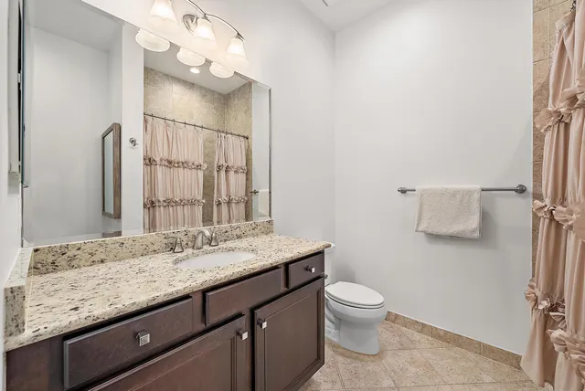 a bathroom with a granite countertop sink a toilet and a mirror