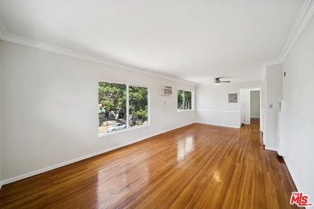 a view of empty room with wooden floor and fan