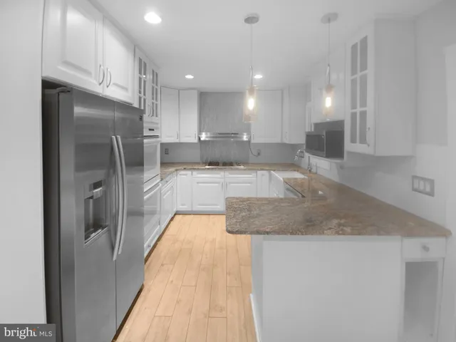 a large kitchen with stainless steel appliances granite countertop a sink refrigerator and cabinets