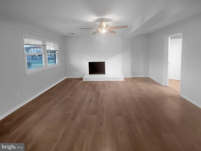 a view of an empty room with a chandelier fan and a window