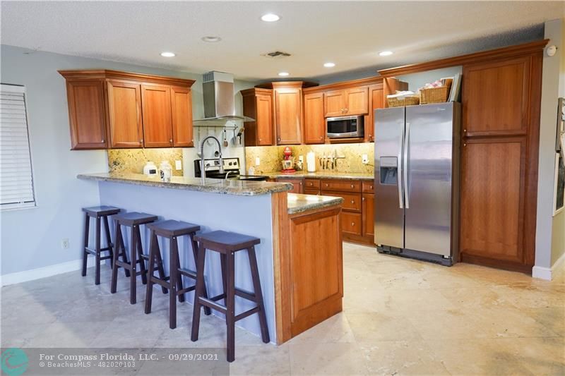 a kitchen with stainless steel appliances granite countertop a table chairs refrigerator and microwave