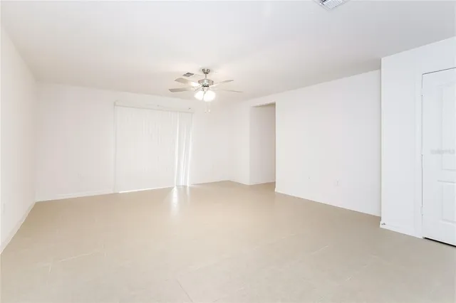 an empty room with a chandelier fan and windows