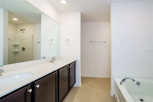 a en suite bathroom with a double vanity sink a mirror and a bathtub