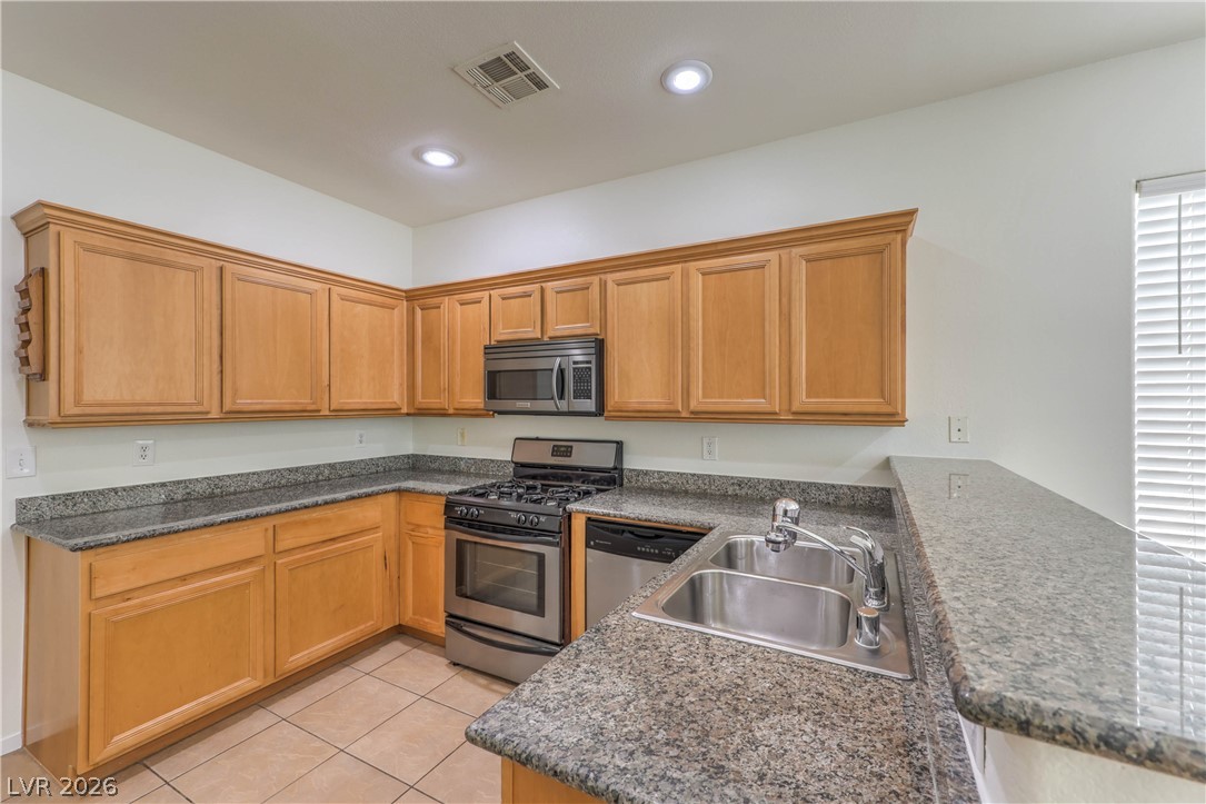 10939 Paradise Road Henderson, NV 89052 - Photo 8 of 36 A corner kitchen showcases plentiful wood cabinetry and durable granite countertops, ideal for everyday cooking.