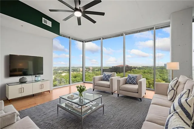 a living room with furniture floor to ceiling window and a flat screen tv
