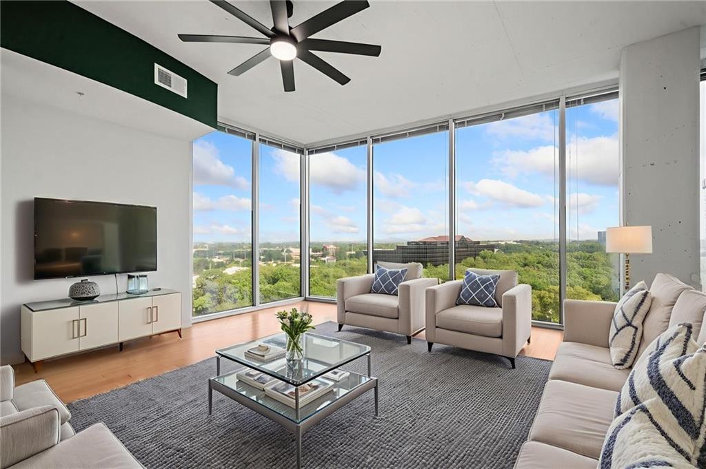 a living room with furniture floor to ceiling window and a flat screen tv