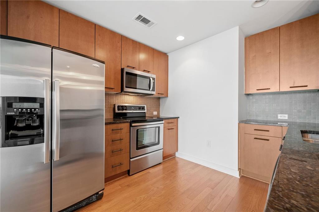 3300 Windy Ridge Parkway Southeast, Unit 1113 Atlanta, GA 30339 - Photo 11 of 39 a kitchen with stainless steel appliances granite countertop a refrigerator a stove and a sink with wooden floor