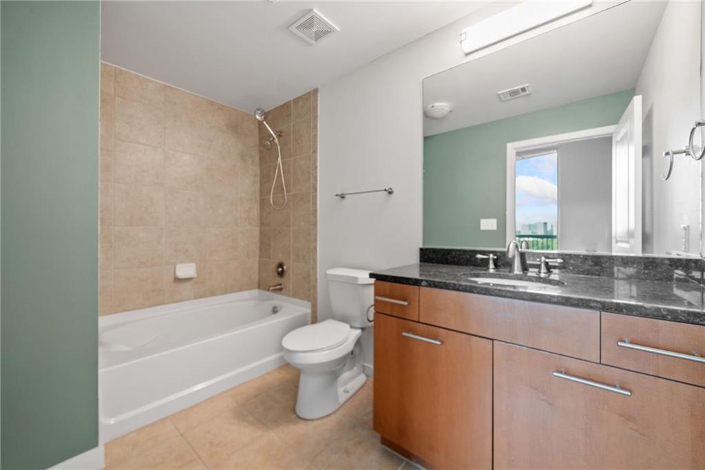3300 Windy Ridge Parkway Southeast, Unit 1113 Atlanta, GA 30339 - Photo 20 of 39 a bathroom with a granite countertop sink a toilet and bathtub
