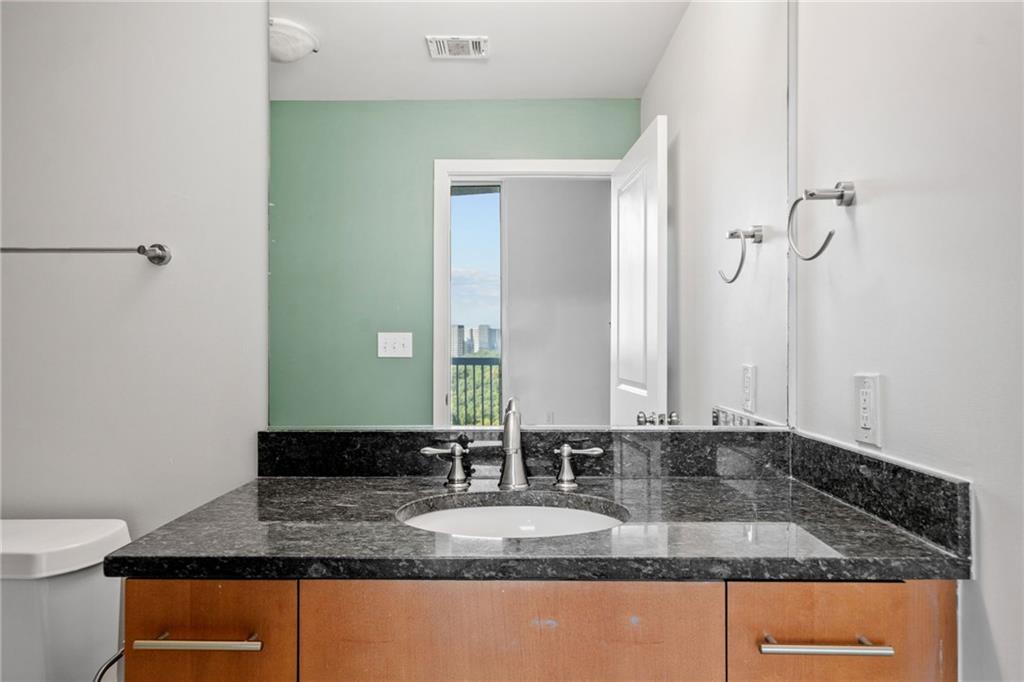 3300 Windy Ridge Parkway Southeast, Unit 1113 Atlanta, GA 30339 - Photo 21 of 39 a bathroom with a granite countertop sink and a mirror