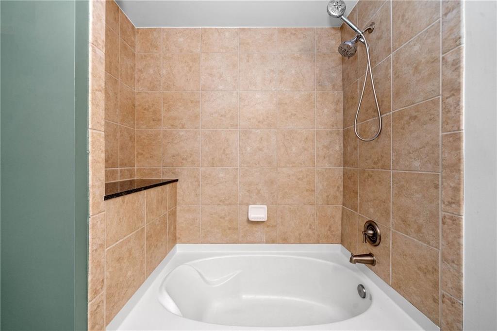 3300 Windy Ridge Parkway Southeast, Unit 1113 Atlanta, GA 30339 - Photo 21 of 39 a bathroom with a white bath tub and a shower