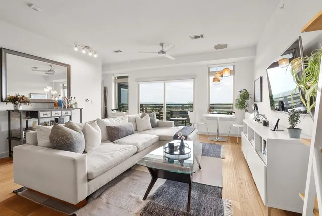 a living room with furniture flat screen tv and a large window