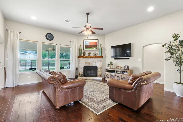 a living room with furniture a fireplace a flat screen tv and wooden floor