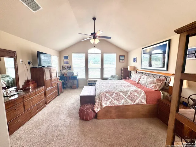 a spacious bedroom with a bed couch dresser and a flat tv screen