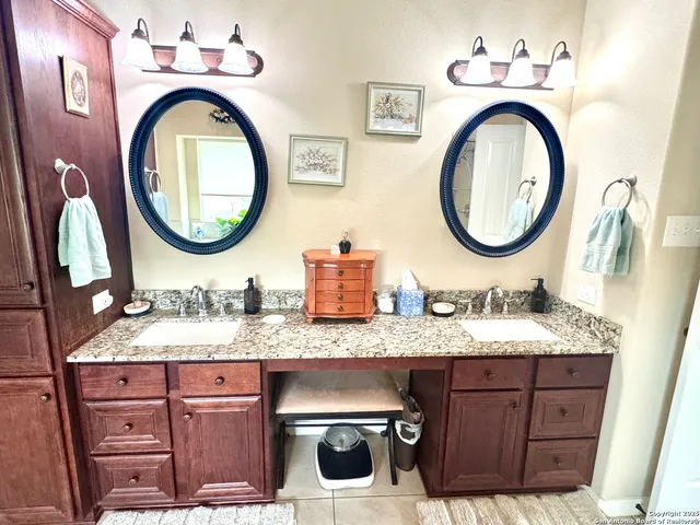 a bathroom with a granite countertop double vanity sink and a mirror