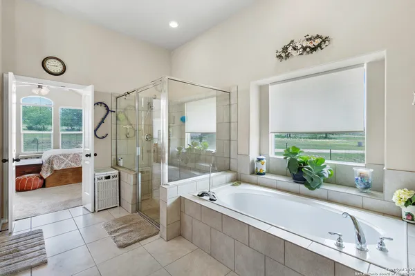 a bathroom with a tub a double vanity sink large mirror and a shower