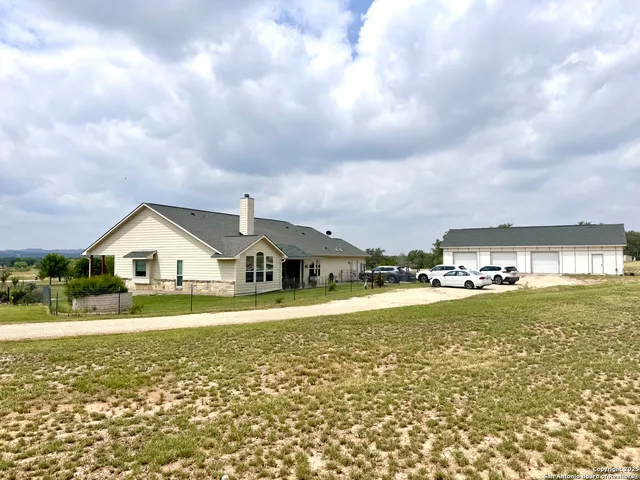 a front view of a house with a big yard and a large tree