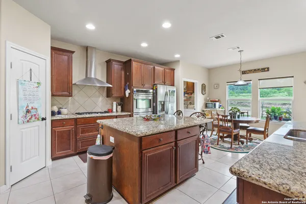 a kitchen with stainless steel appliances granite countertop a stove top oven a sink dishwasher and cabinets with wooden floor