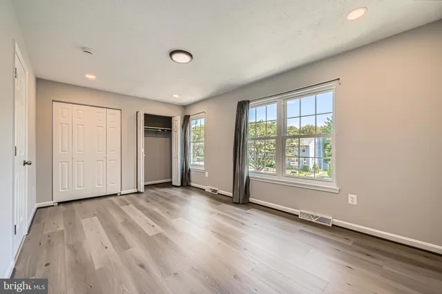 an empty room with wooden floor and windows