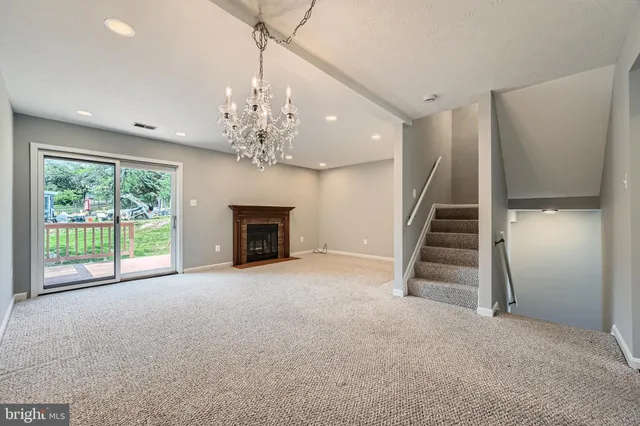 a view of an empty room with fireplace stairs and windows