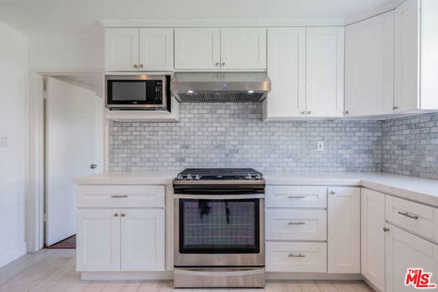 a kitchen with white cabinets and stainless steel appliances