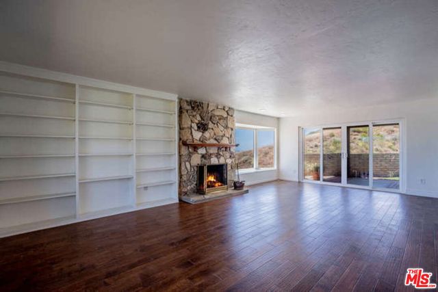 a view of a big room with wooden floor fire place and windows