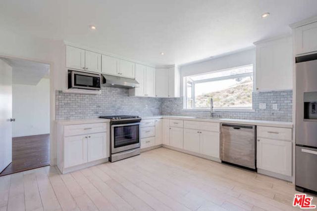 a kitchen with granite countertop white cabinets and appliances