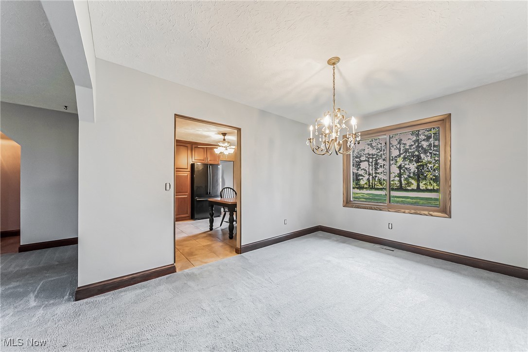 43385 Kipton Nickle Plate Road Lagrange, OH 44050 - Photo 10 of 37 Dining room with a textured ceiling, an inviting chandelier, and light carpet
